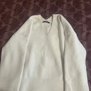 Vit v-ringad stickad tröja BikBok - Supermjuk vit stickad tröja från BikBok i storlek S. Tröjan har v-ringning, långa ärmar och bred ribbad kant nedtill. Perfekt för lager-på-lager och chill vibes. Enkel att matcha med jeans eller kjol.