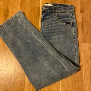 Levi's blå jeans straight fit - Klassiska blå jeans från Levi's i straight fit med fem fickor och snygga slitningar. Jeansen har normalhög midja och är tillverkade i slitstarkt denim. Perfekta för dig som gillar en tidlös och avslappnad stil.