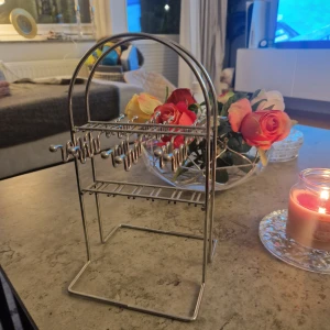 Snygg silverfärgad örhängeshållare - Stilren örhängeshållare i metall med bågformad design och flera krokar för att organisera dina örhängen. Perfekt för att hålla koll på dina smycken och ge rummet en modern touch. Passar både små och stora örhängen. Den har skavanker och slitage men påverkar ej funktionen.