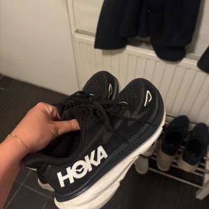 HOKA Clifton 9 strl 38 - Ett par jättesnygga och sparsamt använda svart/vita HOKA Clifton 9 i storlek 38🥰Suupersköna, säljes då jag fick fel storlek. Nypris 2000 kr. 
