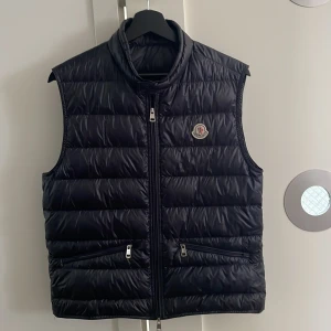 Moncler gui väst - Säljer denna Moncler gui västen då den har blivit för liten för mig. 9/10 skick använd ett fåtal gånger. Mörkblå och storlek 1 vilket motsvarar S/XS Man får med påsen och alla extra grejer. Hör av er om det är något speciellt. Kan tänkas gå ner i pris vid snabb affär!