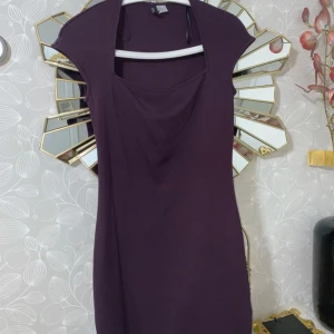 Mörklila kort klänning med drapering - Snygg mörklila kort klänning från H&M med draperad halsringning och cap sleeve. Klänningen har en enkel, figurnära siluett. Perfekt för dig som gillar trendiga plagg.✨