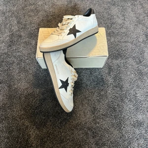 Golden Goose Ballstar vita/svarta sneakers - Golden Goose Ballstar sneakers I vit och svart design. Storlek 45 andvända fåtal gånger ( sick som helt nya ). Säljs då dom inte passar min stil och är sugen på Maison Mairgrllas Gats. Bara hör av er vid frågor mm