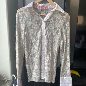 Vit spetsblus med krage från Sexy Lingerie & Fashion - Från Danmark!!Blusen har långa ärmar och breda manschetter i satinliknande material.