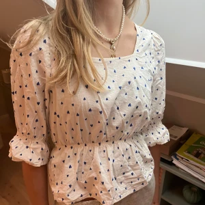 Vit blus med blå hjärtan från Lollys Laundry - Supersöt vit blus från Lollys Laundry med blå hjärtmönster. Väldigt bra kvalitet, den har dock en liten fläck men inget man tänker på (se sista bilden). Köpte för över 1000 kronor 