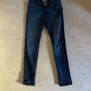 Blå slim fit jeans från Jack & Jones - Snygga blå jeans från Jack & Jones i modellen Slim Glenn. Klassisk femficksdesign med knappar. Jeansen har en smal passform och är tillverkade i bomull. Pris kan diskuteras!