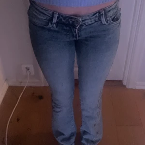 Ljusblå lågmidjade jeans med broderade bakfickor - Säljer ett par ljusblå jeans med väldigt låg midja och snygga broderade detaljer på bakfickorna. Jeansen har klassisk femficksdesign, dragkedja och knapp framtill. Perfekta för en avslappnad och trendig look. (Använda 3 gånger) nypris 599kr