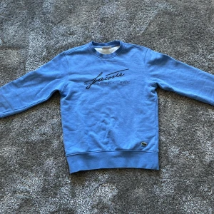 Blå sweatshirt från Lacoste - Säljer en blå sweatshirt från Lacoste, använd fåtal gånger utan defekter. Hade sagt skick är 10/10. Passar mer som S än XS