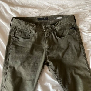 Replay Anbass grå/gröna jeans - Snygga grå/gröna jeans från Replay, modell Anbass. Klassisk femficksdesign med knapp och dragkedja i gylfen. Byxorna har raka ben och är tillverkade i ett mjukt bomullsmaterial med lite stretch för extra komfort.