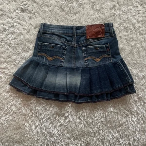 Mörkblå volangkjol i jeans - Lågmidjad jeanskjol omsydd från ett par jeans.  Midjemått tvärsöver- 34cm Längd-34cm