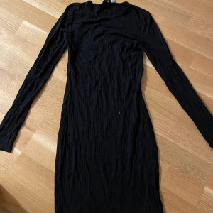 Svart ribbad långärmad klänning från NA-KD - Säljer en svart ribbad långärmad klänning från NA-KD i storlek XXS. Klänningen har en tight passform och är tillverkad i ett stretchigt material som sitter snyggt på kroppen. Perfekt för dig som gillar en enkel och stilren look.