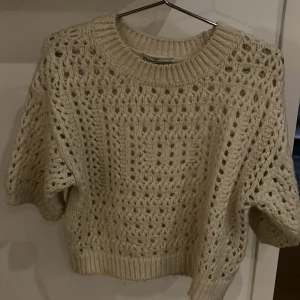 Vit stickad tröja från Zara strl xs-s - Säljer en vit stickad tröja från Zara med hålmönster och bred ribbad kant vid hals, ärmslut och nederkant. Tröjan har en croppad passform och lite vidare ärmar. Storlek XS-S