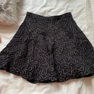 Svart kjol med vitt mönster från H&M - Säljer en svart kjol från H&M med vitt, abstrakt mönster över hela tyget. Absolut en favorit kjol, säljer för den är för lite för mig 