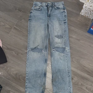 Ljusblå slitna jeans från g perfect jeans - Säljer ett par ljusblå jeans från gina med raka ben och stora slitningar på båda knäna. Jeansen har klassisk femficksdesign och normal passform. Perfekta för en avslappnad och trendig look. Säljer dom för dom har blivit för stora på mig. Original pris 600kr