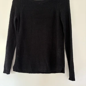 Svart stickad tröja från Vero Moda - En svart stickad tröja från Vero Moda i storlek XS. Tröjan har rund halsringning och långa ärmar. Enkel och stilren modell som passar perfekt till lager-på-lager under kyligare dagar.