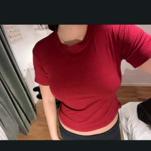 Röd ribbad t-shirt - Säljer en snygg röd ribbad t-shirt med rund halsringning och korta ärmar. Toppen har en tight passform och är perfekt att matcha med både jeans och kjol. Enkel men stilren design som passar till många tillfällen. Passar XS och S