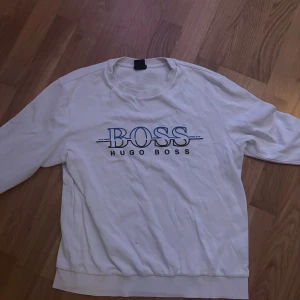 Vit Hugo Boss tröja - Vit långärmad sweatshirt från Hugo Boss med stor BOSS-logga framtill. Storlek L men passar  M bra också