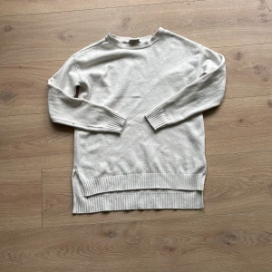 Vit stickad tröja med slits - En stilren vit stickad tröja med lång ärm och ribbade muddar. Tröjan har en avslappnad passform och snygga slitsar i sidorna.  