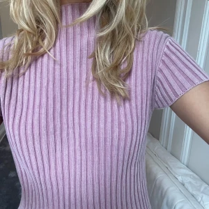 Ribbad rosa topp med knappar i sidan - Supersöt ribbad topp i ljusrosa från samsoe samsoes nya kollektion, med korta ärmar najs detsljer. Toppen är lite croppad och har snygga knappar längs ena sidan som extra detalj. Perfekt till jeans eller kjol för en chill outfit!! Aldrig använd prislappen ej kvar men perfekt skick, nypris runt 2000