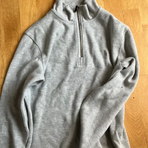 Ralph Lauren - Snygg grå långärmad tröja från Polo Ralph Lauren med half zip och hög krage. Broderad logga på bröstet. Perfekt för lager-på-lager och chill vardagsstil. Mjuk bomullskänsla och klassisk passform.