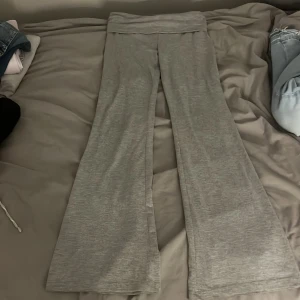 Grå yoggapants från Gina Tricot - Grå yoggapants Gina Tricot med bred, vikt midja och utsvängda ben. Byxorna är tillverkade i mjukt bomullsmaterial och har en relaxed fit som är perfekt för chill dagar. Snyggt basic-plagg som är lätt att matcha med hoodies eller crop tops.