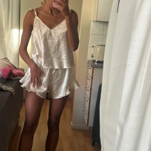 Champagnefärgad volangs pyjamas i satin - Champagnefärgad volangs pyjamas i satin material med volangkant. De har elastisk midja och en flowy, lös passform 