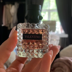 Valentino Eau de Parfum 30ml - Lyxig parfym från Valentino i en snygg, fyrkantig glasflaska med nitar och rosa doftvätska. Flaskan rymmer 30 ml och har en svart kork med coola detaljer. Perfekt för dig som gillar exklusiva och trendiga dofter.