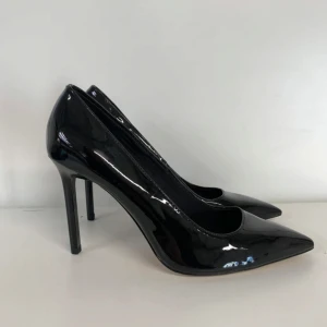 Svarta klackskor - Snygga svarta pumps i glansigt lackmaterial med spetsig tå och hög klack. Klassisk och elegant modell som ger en stilren look. Perfekta för dig som vill sticka ut med en tidlös vibe.