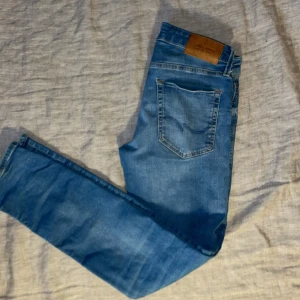 Blå slim-fit jeans från Jack & Jones - Snygga blå skinny jeans från Jack & Jones i klassisk femficksmodell. Jeansen har normalhög midja, smal passform och är tillverkade i stretchigt denim för extra komfort. Perfekta till sneakers och hoodie för en avslappnad look.                            Kan gå ner i pris vid snabb affär!!