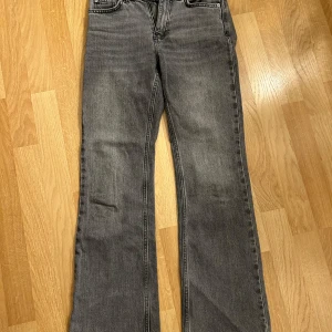 Grå bootcut jeans från Gina Tricot - Snygga grå jeans från Gina Tricot i klassisk bootcut-modell. Jeansen har en rak passform upptill och utsvängda ben, tillverkade i mjukt denimtyg. Perfekta för dig som gillar en avslappnad men trendig look.❤️
