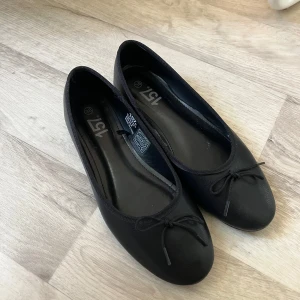Svarta ballerinaskor med rosett lager157 - Klassiska svarta ballerinaskor från 157 med rund tå och liten rosett framtill. Skorna är använda 1 gång. Storlek 38