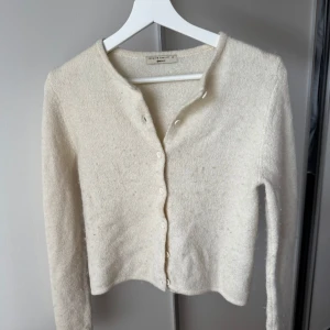 Beige kofta från Gina Tricot XS - Supermjuk och stilren krämvit kofta från Gina Tricot i storlek XS. Koftan har rund halsringning, långa ärmar och knäppning framtill. Perfekt att slänga över en topp för en chill och stilren look.