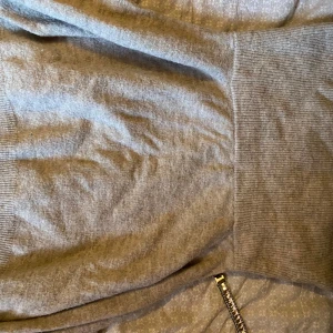 Grå stickad tröja med ribbad midja - Mysig grå stickad tröja med bred ribbad midja och långa ärmar. Perfekt för lager-på-lager och enkel att matcha med jeans eller kjol. Stilren och enkel design som funkar året runt.