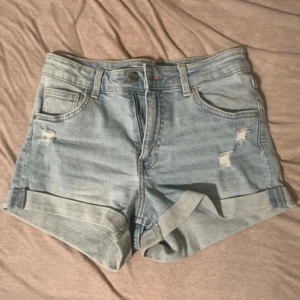Korta ljusblå jeansshorts med slitningar - Korta ljusblå jeansshorts från Bershka i storlek 36.. Snygga och bekväma för vardagsbruk!Köpta för 300kr. Använda 2 gånger så i superbra skick.