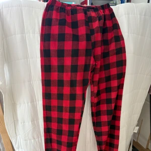 Röd- och svart-rutiga mjukisbyxor - Snygga mjukisbyxor med röd och svart rutig design. Byxorna har resår i midjan och är perfekta för en chill och avslappnad stil. Tillverkade i mjukt bomull/polyester tyg. Storlek L för max 180cm. 