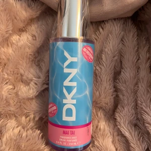 DKNY Mai Tai Fragrance Mist 250ml - Fräsch och tropisk body mist från DKNY i doften Mai Tai. Flaskan är i plast med blå och rosa etikett, har en silvrig spraytopp och rymmer 250 ml. Perfekt för dig som gillar fruktiga och somriga dofter med en snygg, färgglad design.