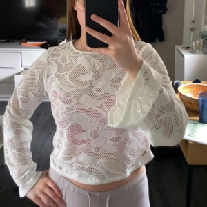 Vit spetsblus med vida ärmar - Säljer en vit blus i spets med rund halsringning och långa, vida ärmar. Perfekt för dig som gillar romantisk stil och vill ha något luftigt och snyggt. Blusen är genombruten och har ett feminint uttryck.