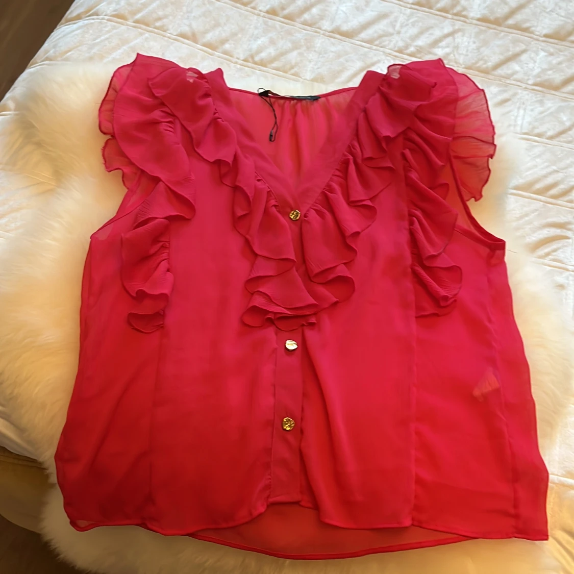 Rosa blus med volanger och guldknappar