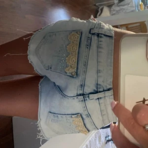 Lowwaist jeansshorts med spets och glitter detaljer - Snygga low waist jeansshorts i strl w30, midja:41cm. Obs dessa är för stora för mig. Kommer fler unika jeansshorts/kjolar så följ!!
