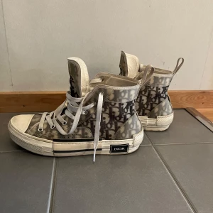 Dior B23 High Top Sneakers - Säljer mina sneakers från Dior. Jag köpte dom begagnade från Vestiaire Collective, så tyvärr har jag ingen box eller kvitto från butik. Jag köpte till Authentication & Quality Control vid köpet. Ok skick, lite släpp vid sulan, se bild. Även skador inne i skon vid hälen, se bild. Nya skosnören