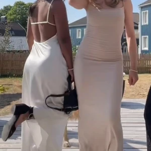 Vit långklänning med öppen rygg  - Säljer en vit långklänning med tunna justerbara axelband och öppen rygg. Klänningen är i satin och  är perfekt för sommaren. 