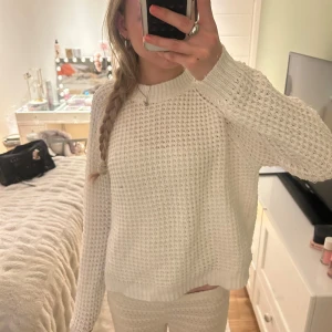 Vit stickad tröja från lager 157 - Mysig vit stickad tröja från lager157  med grovstickat mönster och rund halsringning. Tröjan har långa ärmar och ribbade muddar vid hals, ärmslut och nederkant. Perfekt för kyligare dagar.tycörr lite trasig men inget som man lägger märke till eller något som kan förstöra hela tröjan 