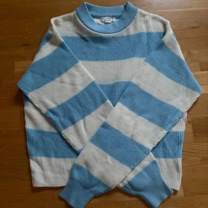 Blåvit randig stickad tröja från Gina Tricot - Säljer en stickad tröja från Gina Tricot med breda blå och vita ränder. Tröjan har lång ärm, rund halsringning och är i ett mjukt, ribbat material.
