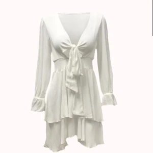 Vit omlottklänning med volang och knyt - Superfin vit kortklänning med omlottknytning framtill, v-ringning och långa ärmar. Klänningen har volangdetaljer och markerad midja med smock. Perfekt för student eller avslutning! Helt ny aldrig använd😊