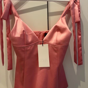 Rosa satinlinnetopp  - Supersöt rosa linnetopp i satin från ZARA, axelband som knyts i rosetter. Toppen har en lätt glansig yta och markerad byst. Aldrig använd och prislappen kvar💕💕