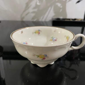 Porslinskopp - en vacker porslinskopp med blommönster och guldkant. Perfekt för dig som gillar vintage eller vill ha en unik kopp till te eller kaffe. Märkningen under koppen visar att det är en kvalitetsprodukt.som jag läser ,så står Karlskrona tror jag .kan möta er i Stockholm city utanför Åhléns 