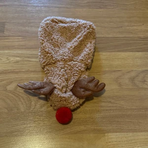 Brun dress till katt/hund från Little&Bigger - Söt och fluffig dress till katt/hund i brunt från Little&Bigger, utformad som en ren med bruna horn och röd nos. Tillverkad i mjukt, teddy-liknande material. Perfekt för julens alla tillfällen. Storlek 20. Aldrig använd. 