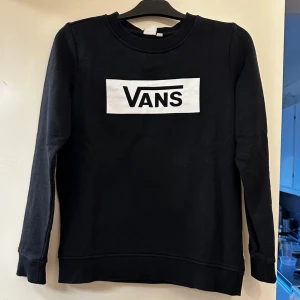 Svart sweatshirt från Vans - Säljer en svart sweatshirt från Vans med klassisk vit logga framtill. Tröjan har rund halsringning och långa ärmar. Perfekt för en avslappnad och stilren look.