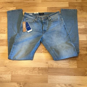 Ljusblå jeans från Jack & Jones - Säljer ett par klassiska ljusblå jeans från Jack & Jones med raka ben och femficksmodell. Jeansen har normal passform och är tillverkade i bomull. Perfekta för dig som gillar en enkel och tidlös stil.