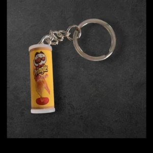 Nyckelring med Pringles Original-burk - Säljer en rolig nyckelring med en miniatyr av en Pringles Original-burk i gult. Perfekt accessoar för dig som älskar snacks och vill ha något unikt på nyckelknippan.